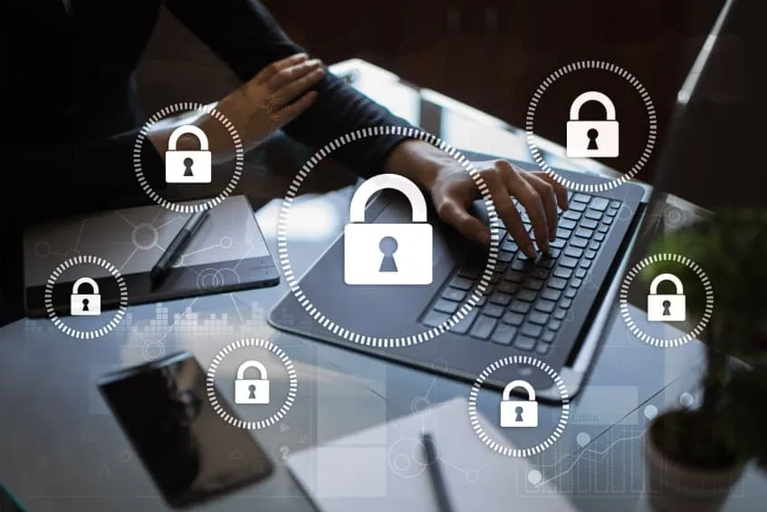 Hands typing on a laptop with padlock icons floating above the keys