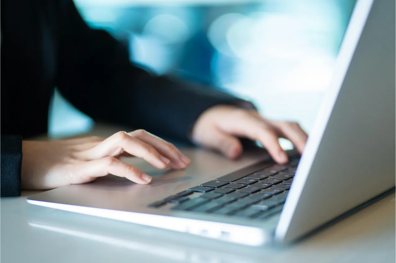 Hands typing on a silver laptop keyboard