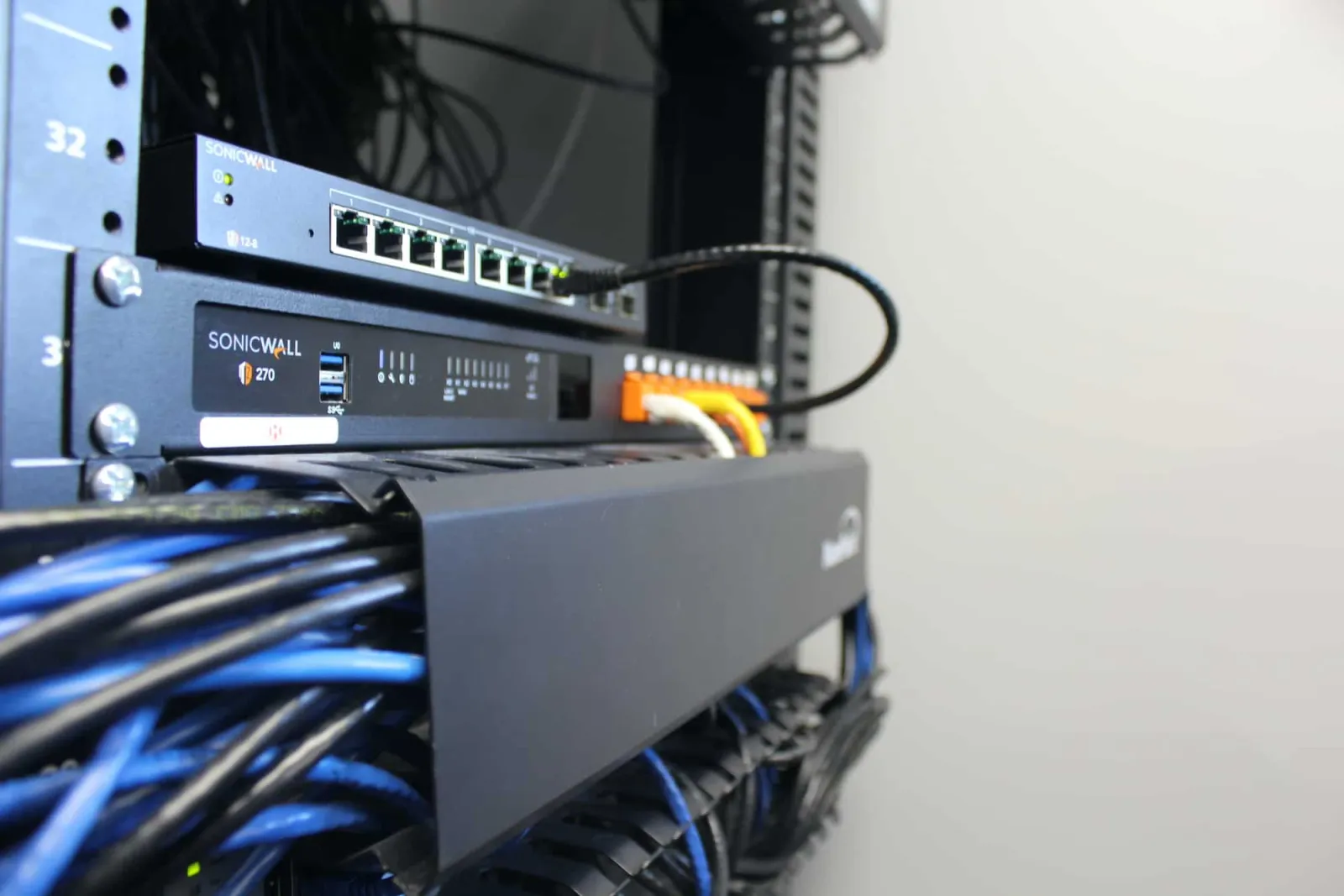 A SonicWall firewall and a network switch with blue patch cables in the CamTech rack