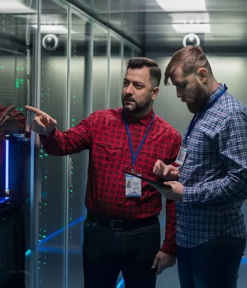 Two technicians discussing equipment in a server room