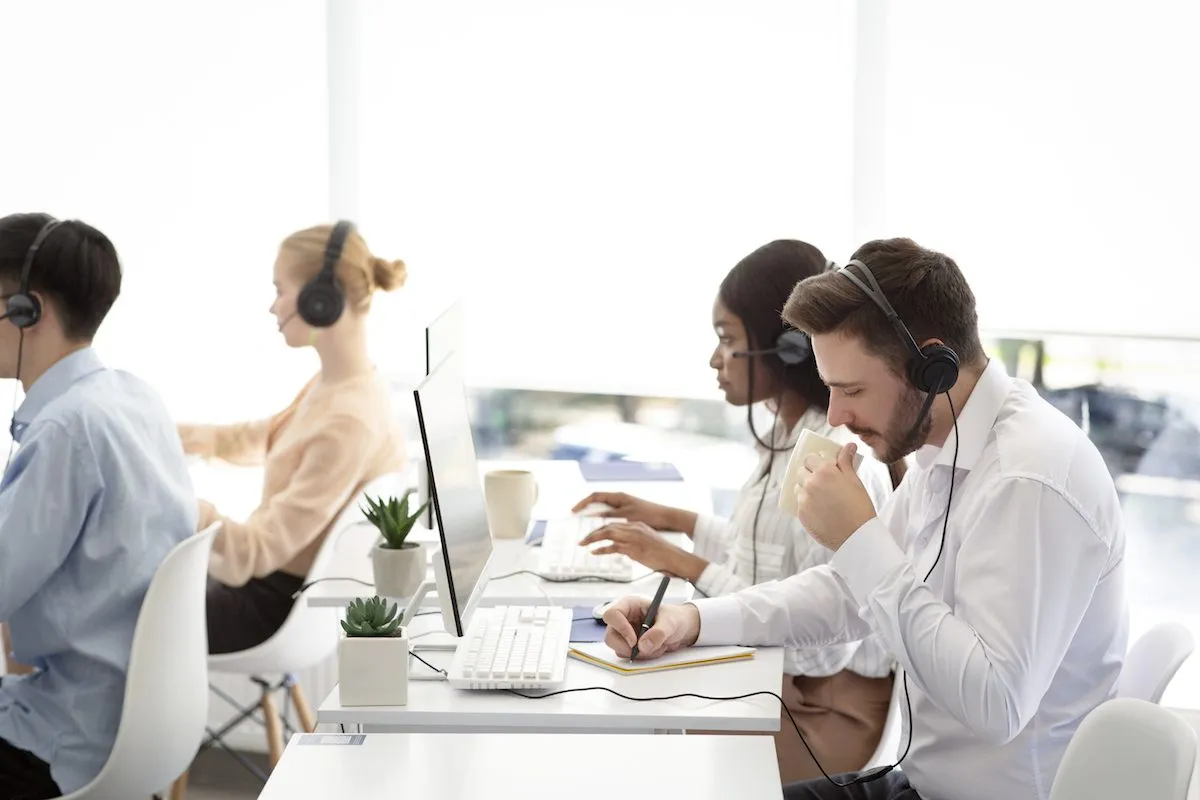 A help desk team in headsets working at a row of computers